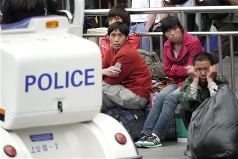 Migrant workers sit near a police electric car patrolling around Shanghai train station on  May 22 in Shanghai, China. North Korean leader Kim Jong Il, whose rare foreign trips are cloaked in secrecy, was traveling to Yangzhou, west of Shanghai Sunday, the Yonhap news agency and broadcaster YTN said, citing diplomatic sources.